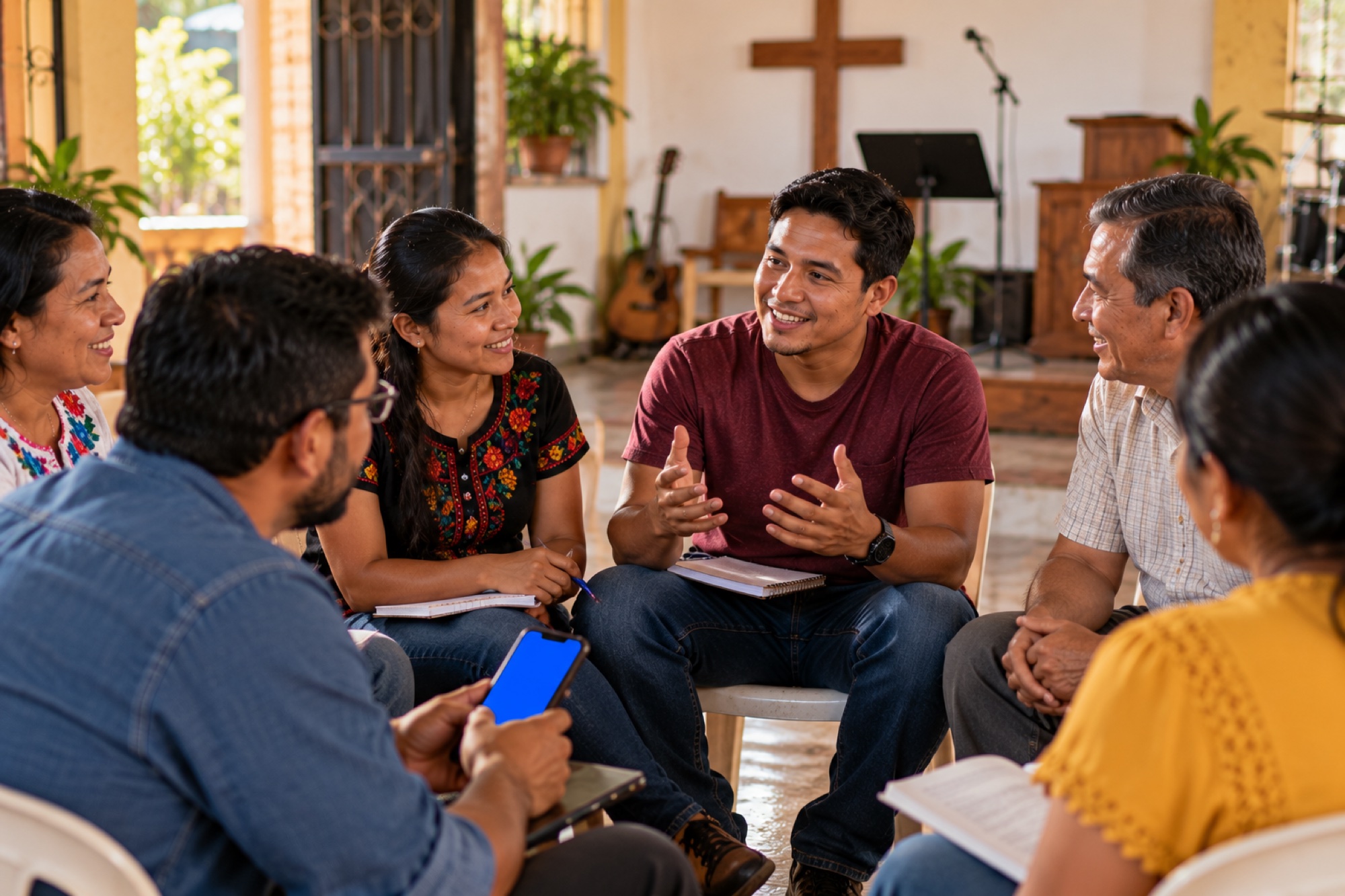 Un grupo pequeño se sienta en un salón de la iglesia, conversando con cuadernos y un teléfono.
